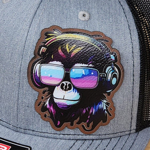 Gray cap with a colorful monkey design wearing sunglasses and headphones on a black background