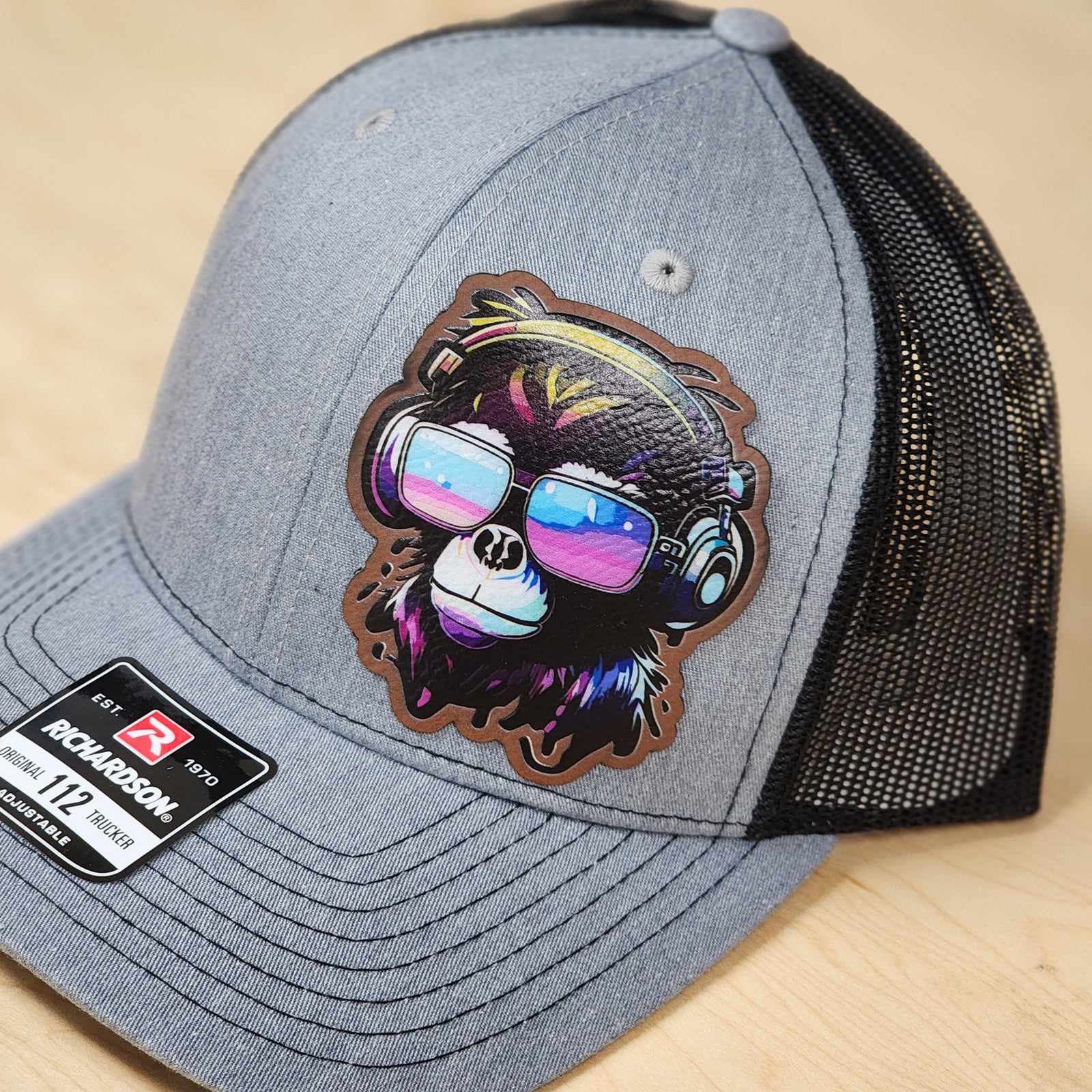 Gray cap with a colorful monkey design wearing sunglasses and headphones on a black background