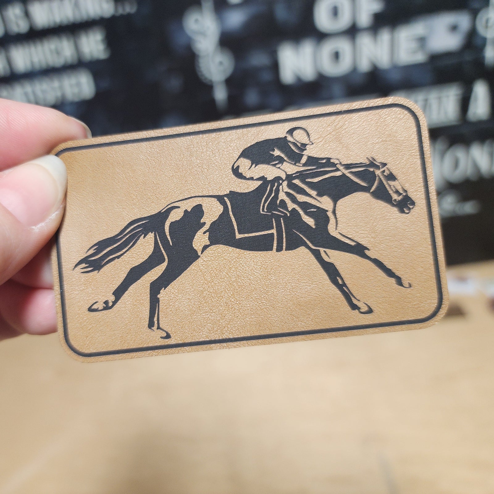 Horse racing leatherette hat patch featuring a jockey on a galloping horse, perfect for equestrian enthusiasts.