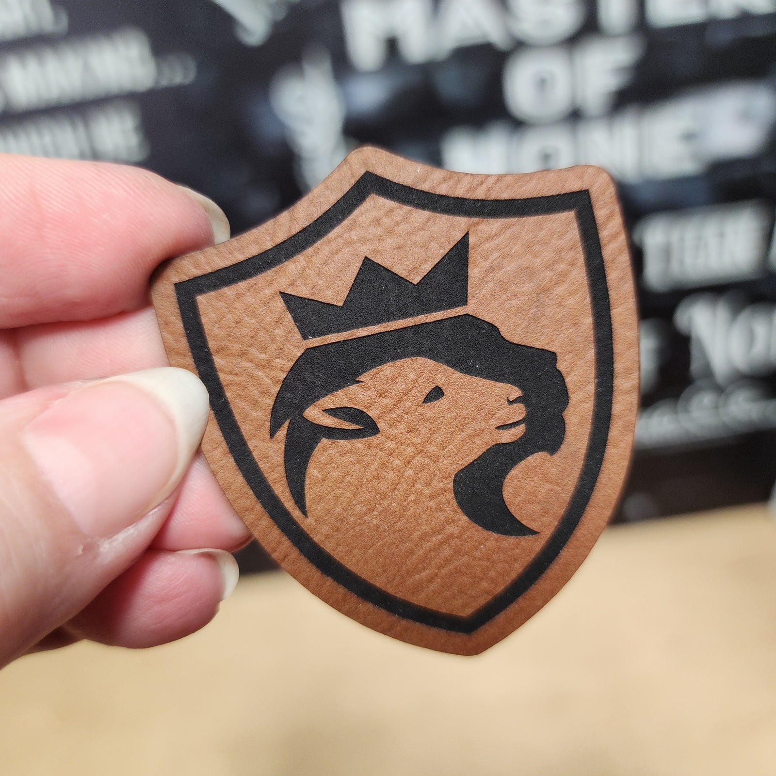 Leatherette shield hat patch featuring a lion with a crown, perfect for trendy hat accessories and custom embroidery.