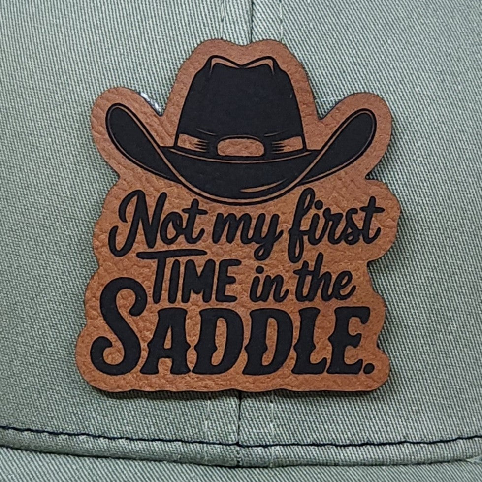 Leatherette hat patch featuring a cowboy hat and the phrase 'Not my first time in the saddle' for cowboy lovers.