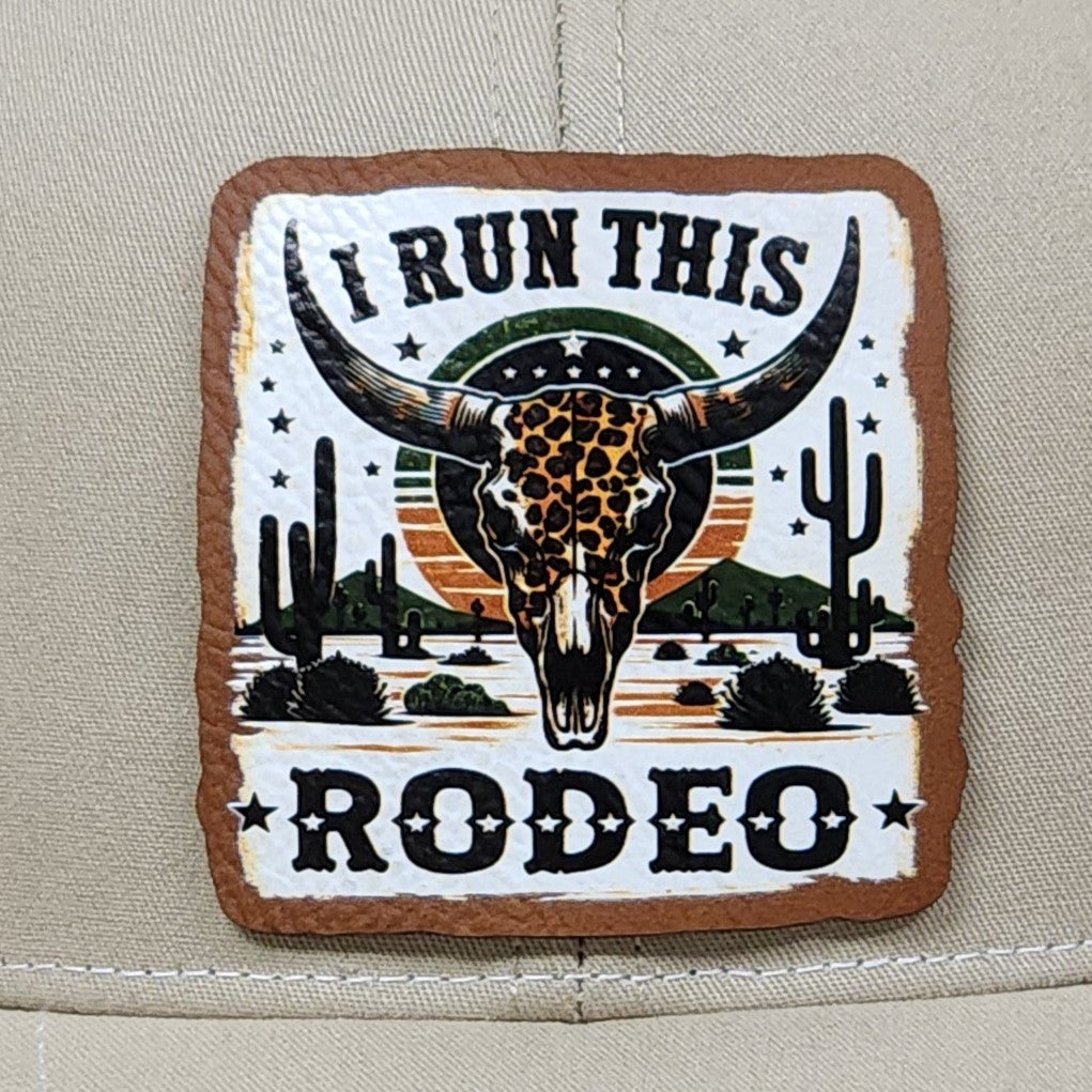 I Run This Rodeo leatherette hat patch featuring a striking longhorn skull and desert scenery, perfect for western fans.