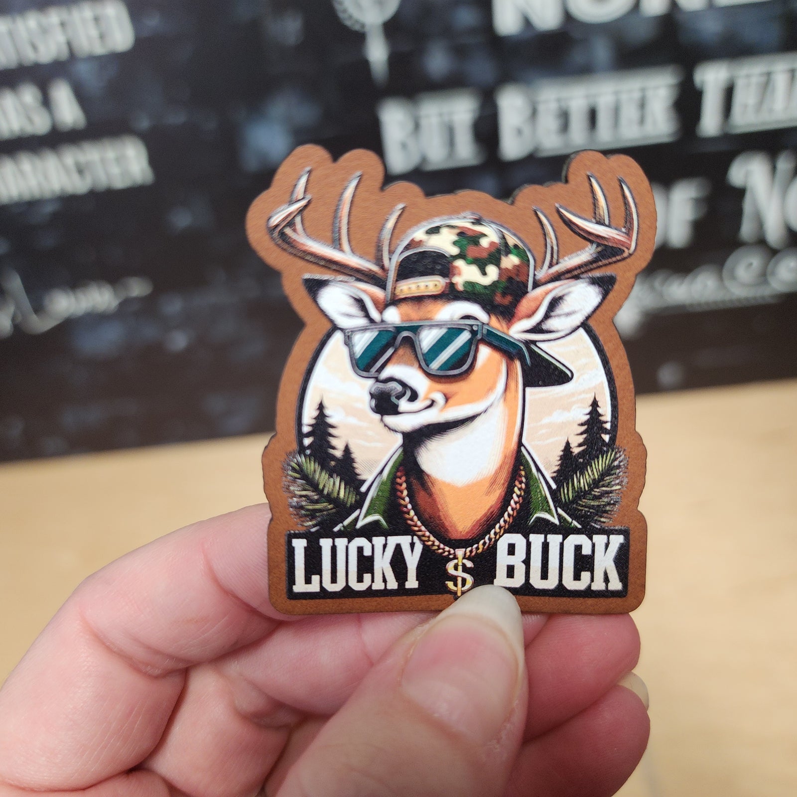 Lucky Buck deer leatherette hat patch with sunglasses and camo cap, perfect for outdoor enthusiasts and hunters.