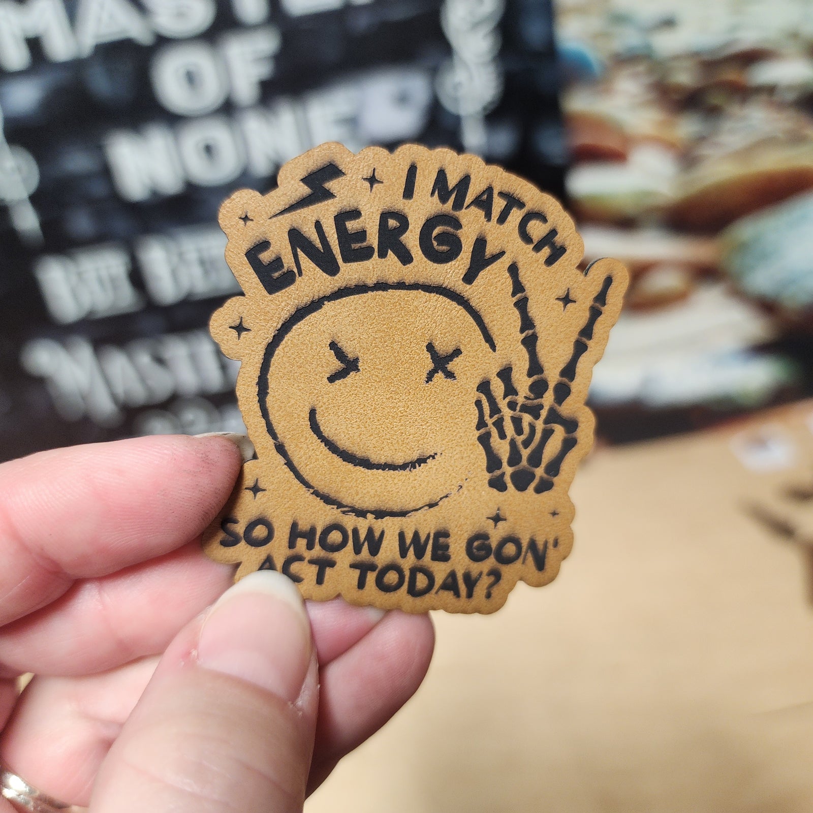 Leatherette patch featuring a smiling face and skeleton hand, perfect for energy-themed accessories.