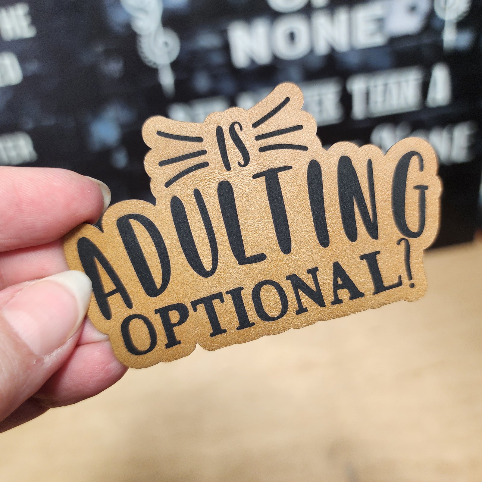 Leatherette hat patch that reads 'Is Adulting Optional?' for fun and quirky accessories.