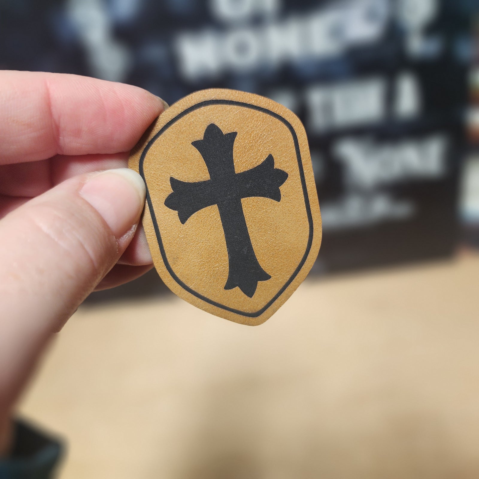 Leatherette shield hat patch featuring a bold black cross, perfect for hats and custom accessories.