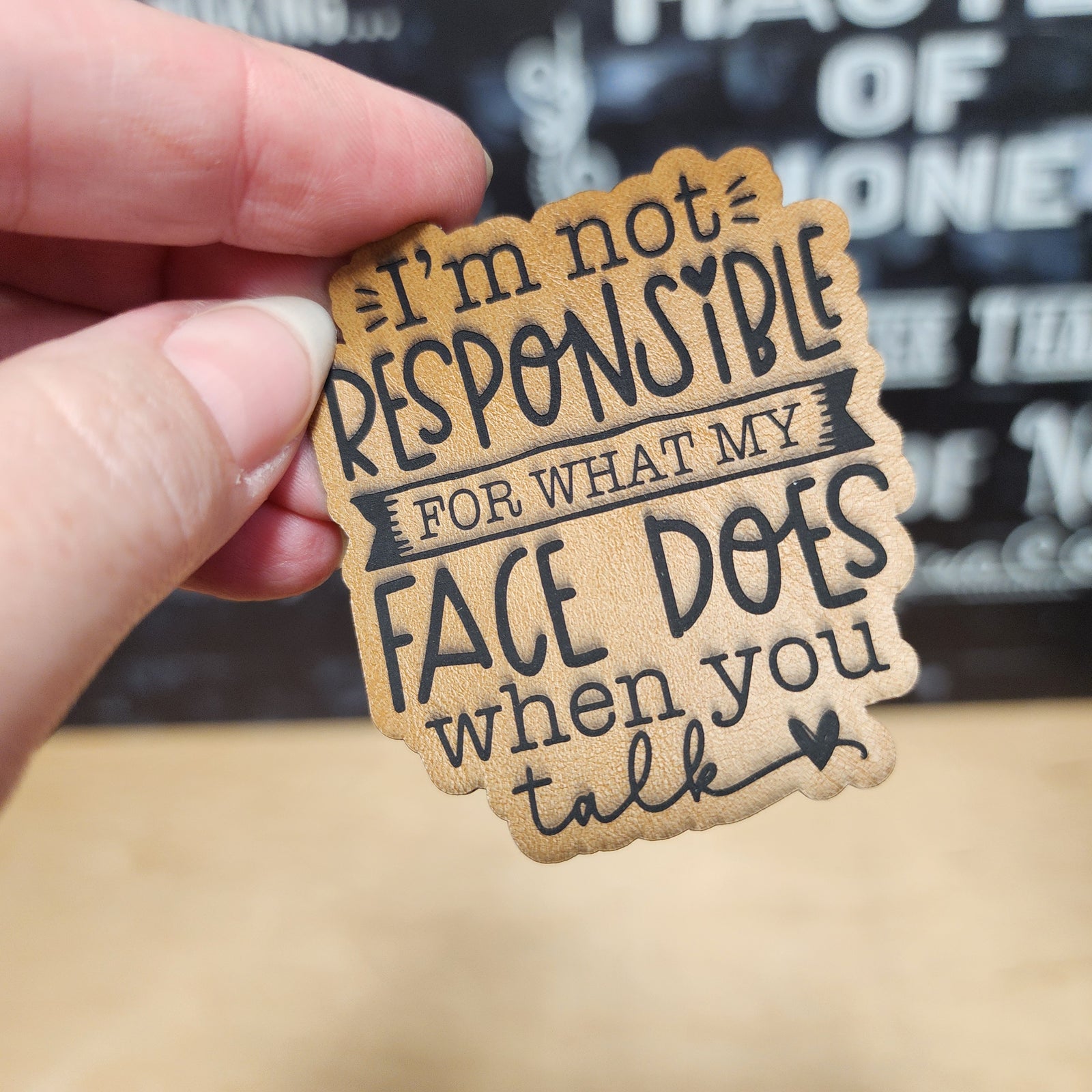 Funny leatherette hat patch with text 'I'm not responsible for what my face does when you talk' perfect for gifts.