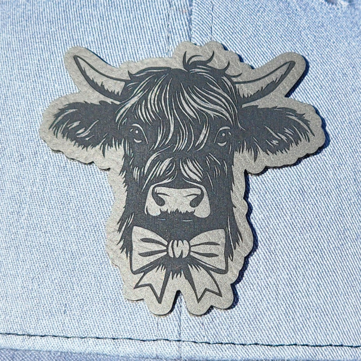 Vintage cow leatherette hat patch with bow tie, perfect for rustic apparel and farm-themed accessories.