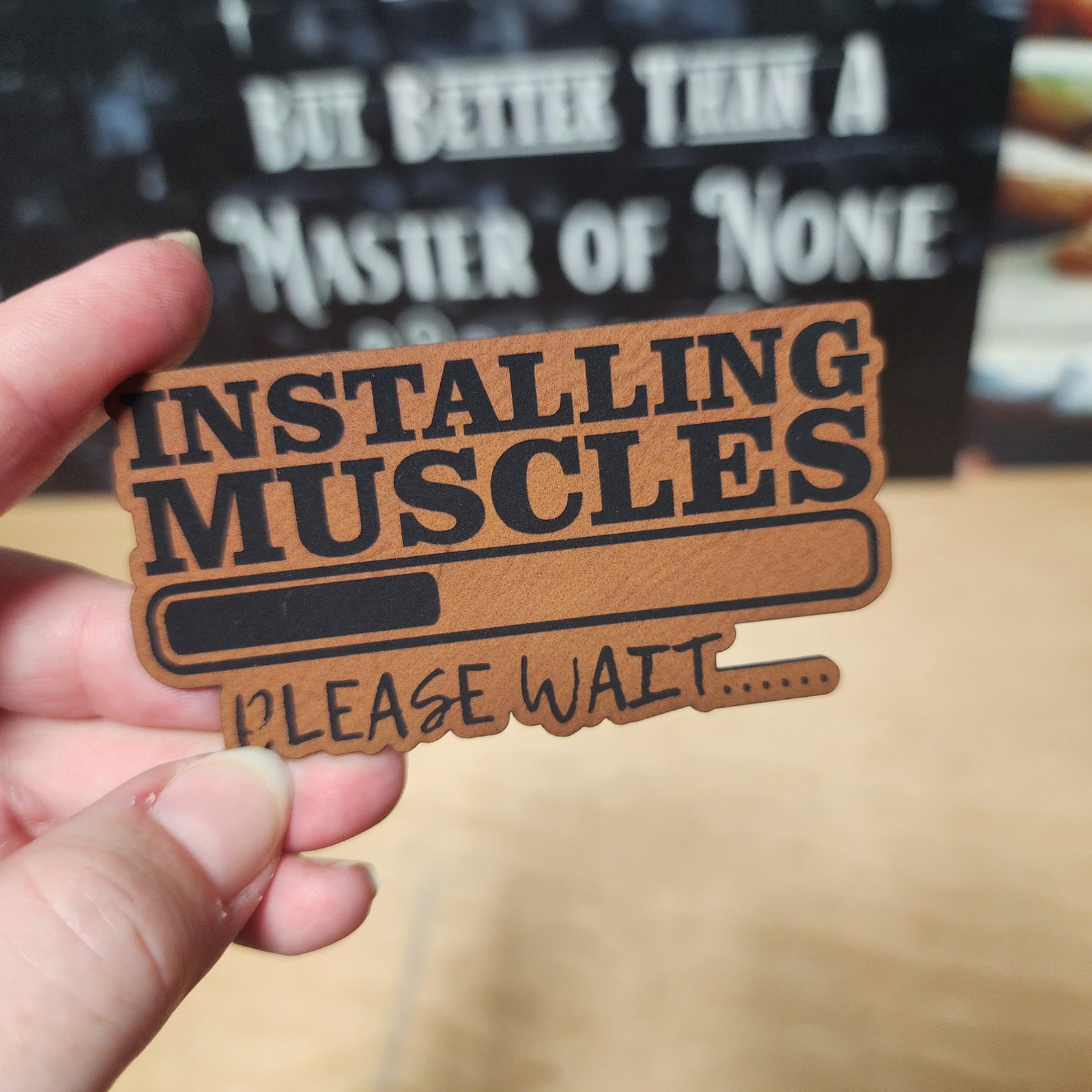 Installing Muscles leatherette hat patch perfect for fitness enthusiasts and humorous gym gifts.