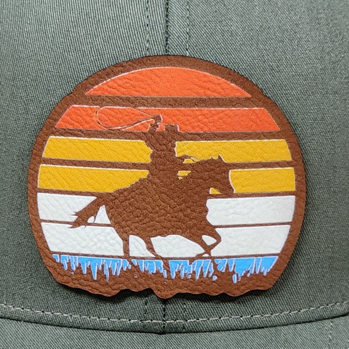 Rodeo cowboy leatherette hat patch with vibrant sunset design for western enthusiasts and outdoor lovers.