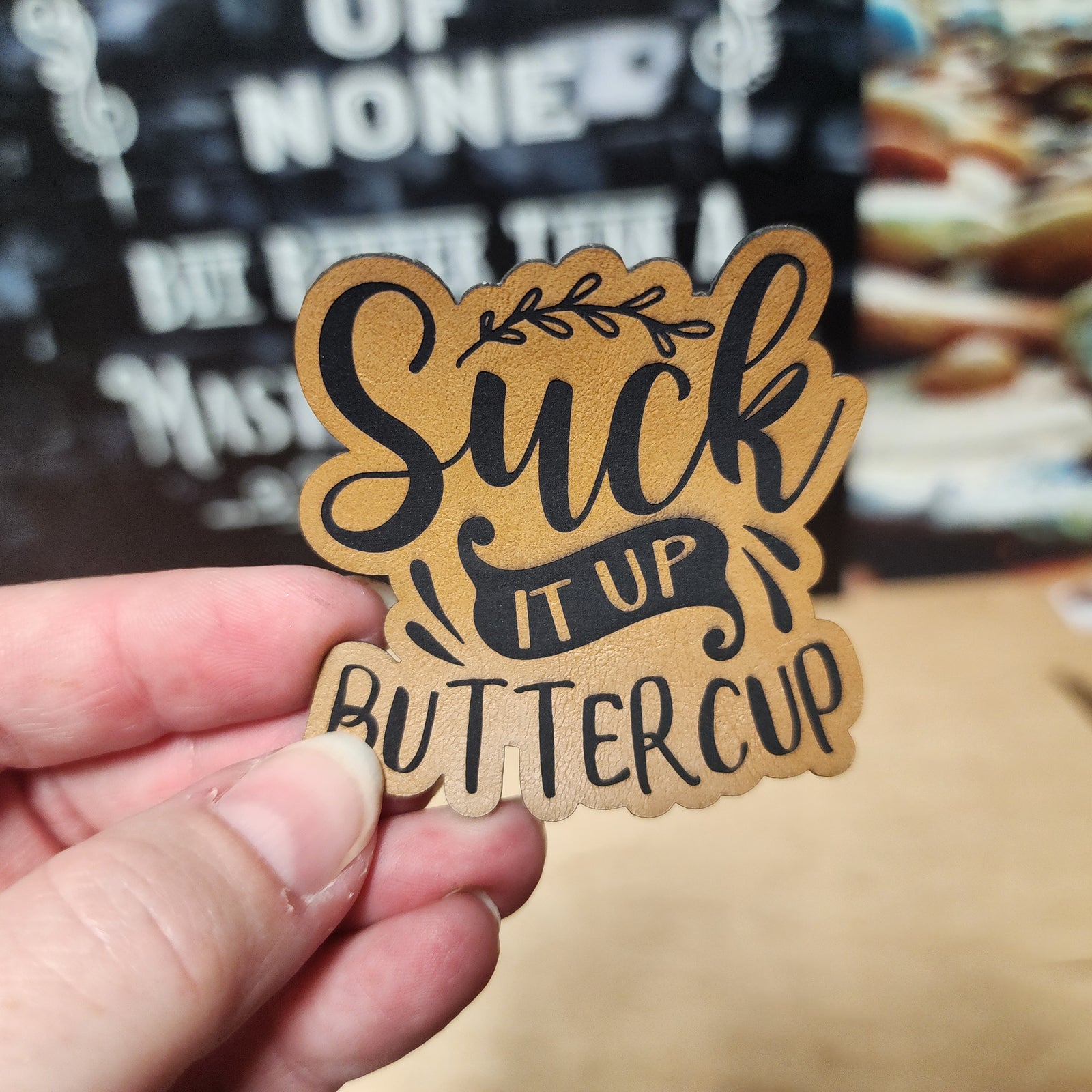Suck it Up Buttercup leatherette hat patch, perfect for adding a humorous touch to hats and accessories.