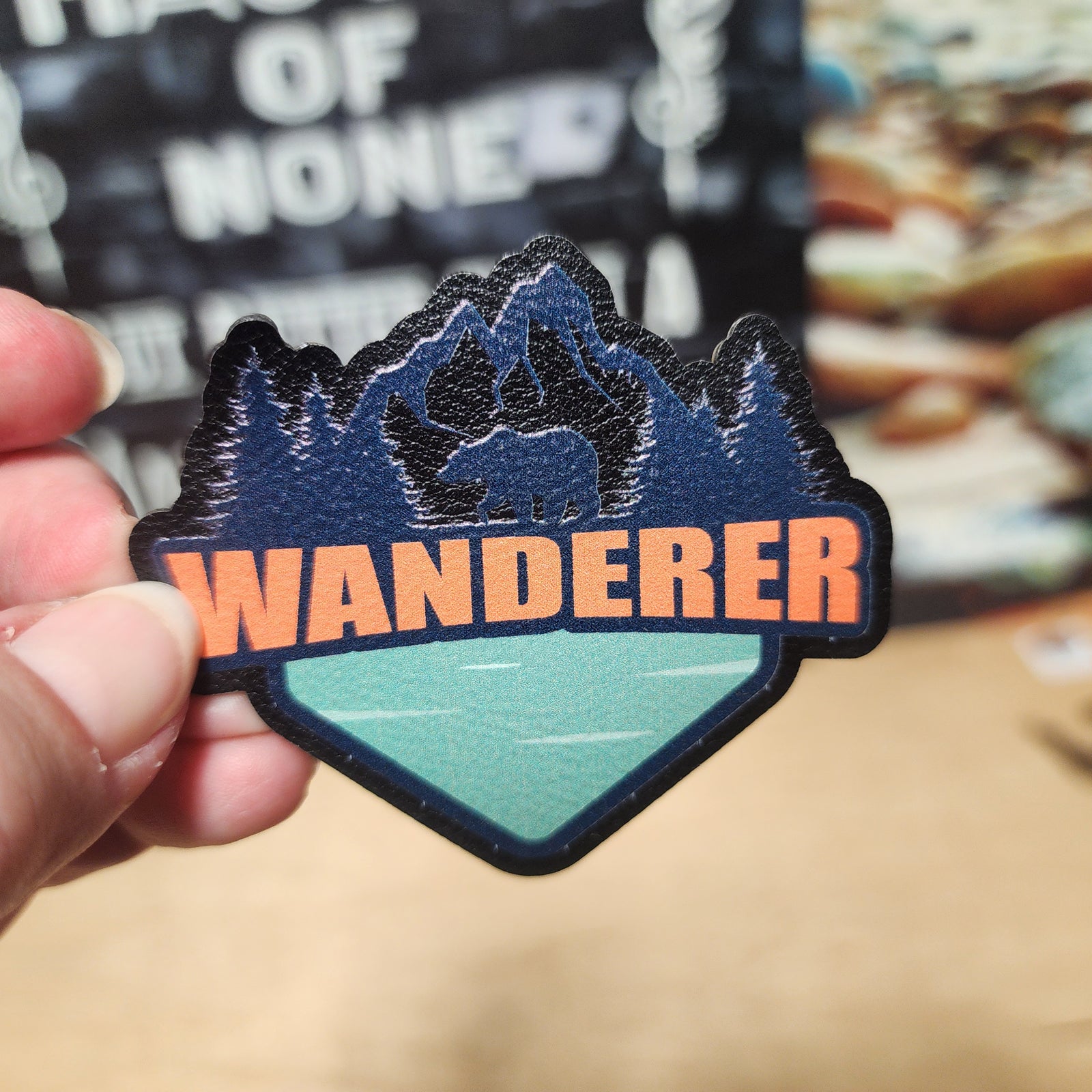 Wanderer leatherette hat patch featuring mountains, a bear, and a scenic lake design for outdoor enthusiasts.