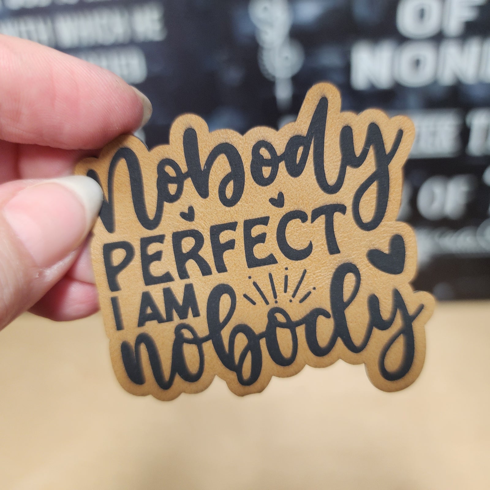 Funny leatherette hat patch saying 'Nobody Perfect I Am Nobody' for humorous apparel and gifts.