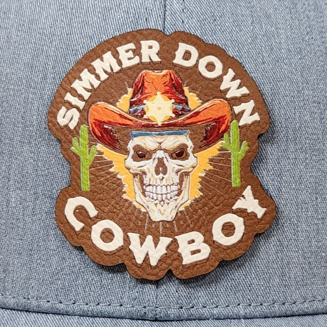 Simmer Down Cowboy leatherette hat patch with skull, cowboy hat, and cactus for western style enthusiasts.
