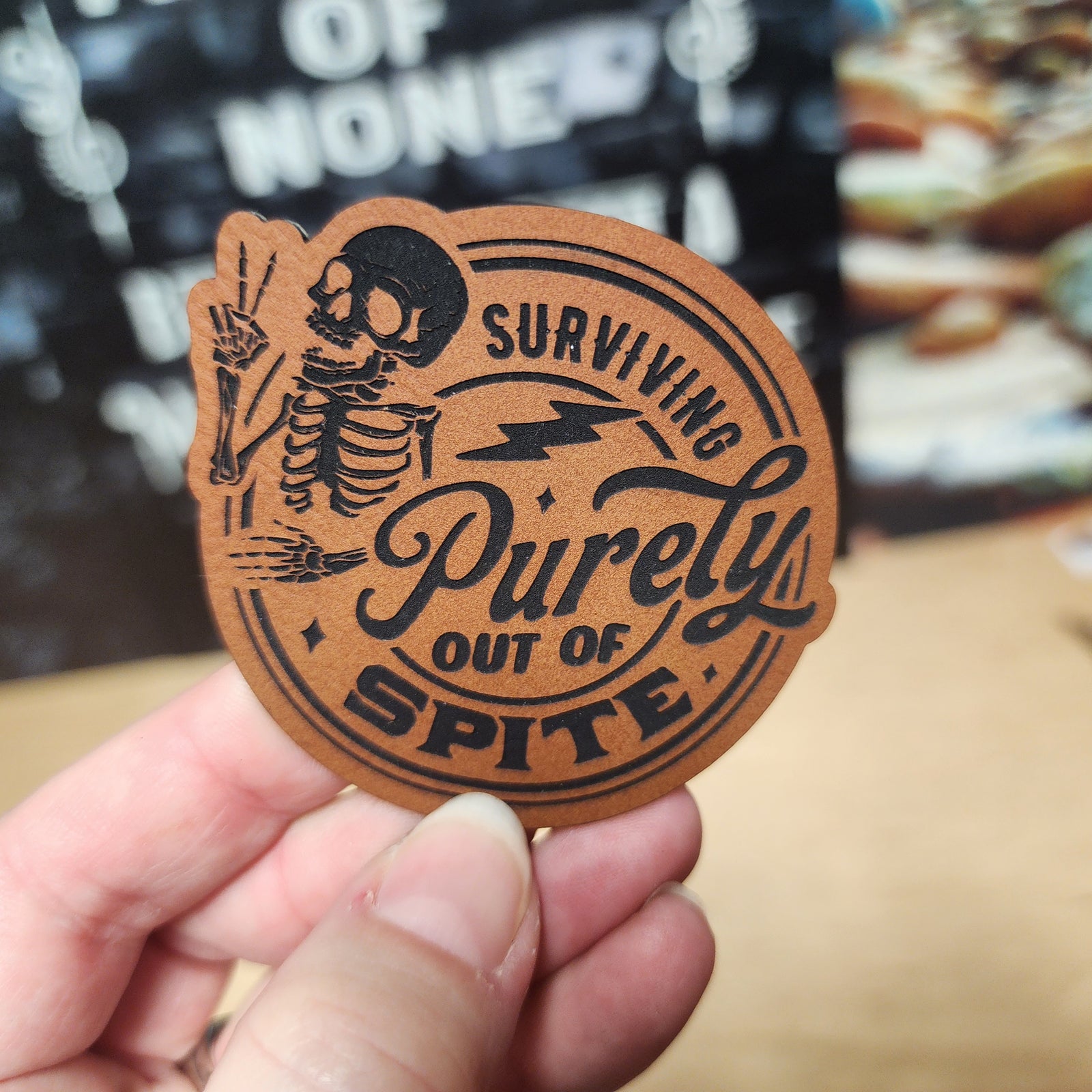 Surviving Out of Spite leatherette hat patch featuring skeleton design for edgy fashion accessories.