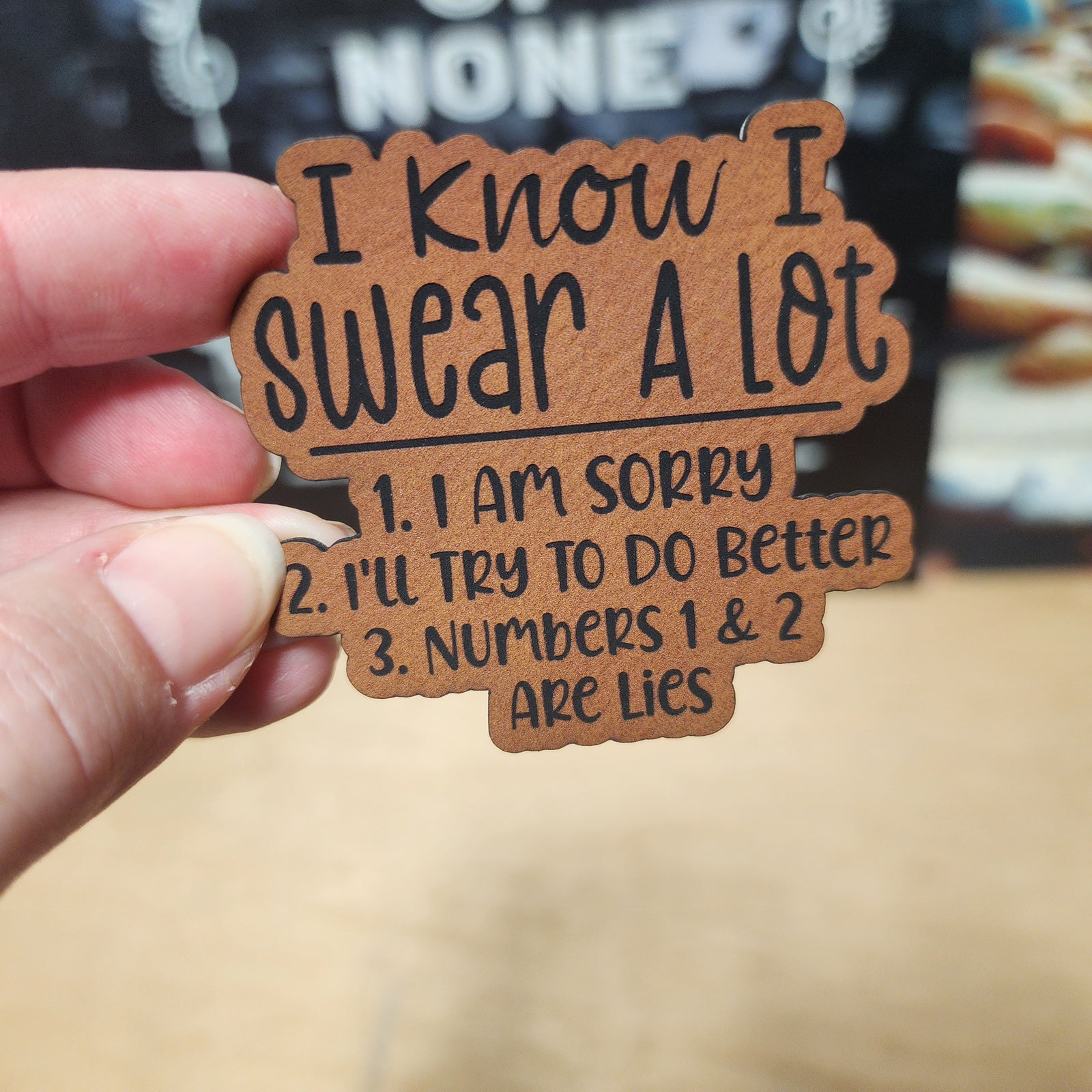 Funny leatherette hat patch saying 'I Know I Swear A Lot' with humorous statements, perfect for casual wear.