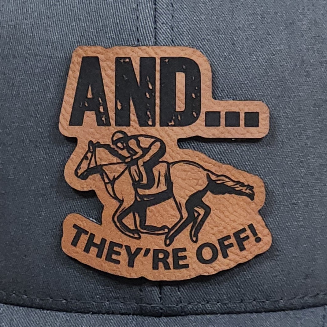 Horse racing leatherette hat patch with the phrase 'AND... THEY'RE OFF!' perfect for sports fans and equestrian lovers.