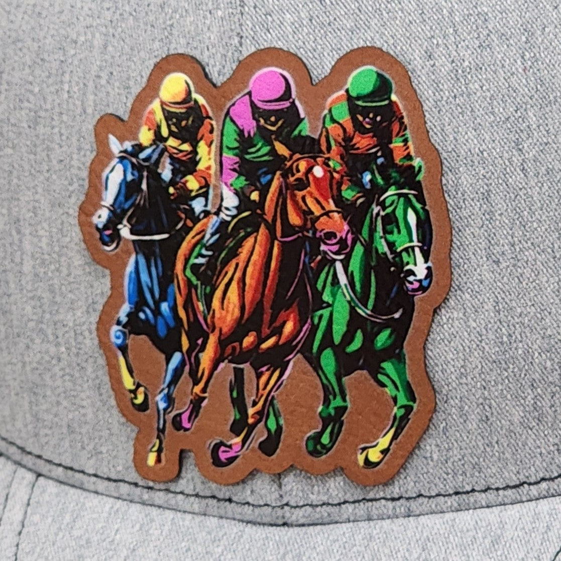 Colorful horse racing leatherette hat patch featuring jockeys in vibrant outfits, perfect for equestrian enthusiasts.
