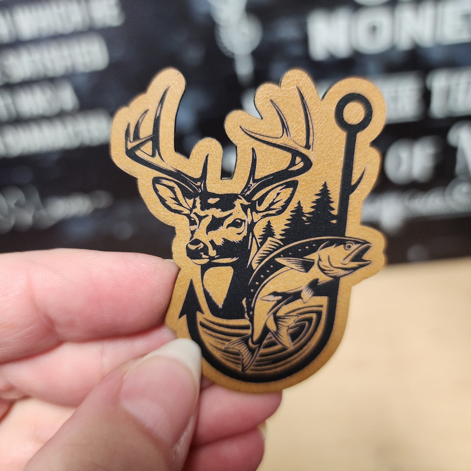 Outdoor adventure leatherette hat patch featuring a deer, fish, and trees for camping enthusiasts.