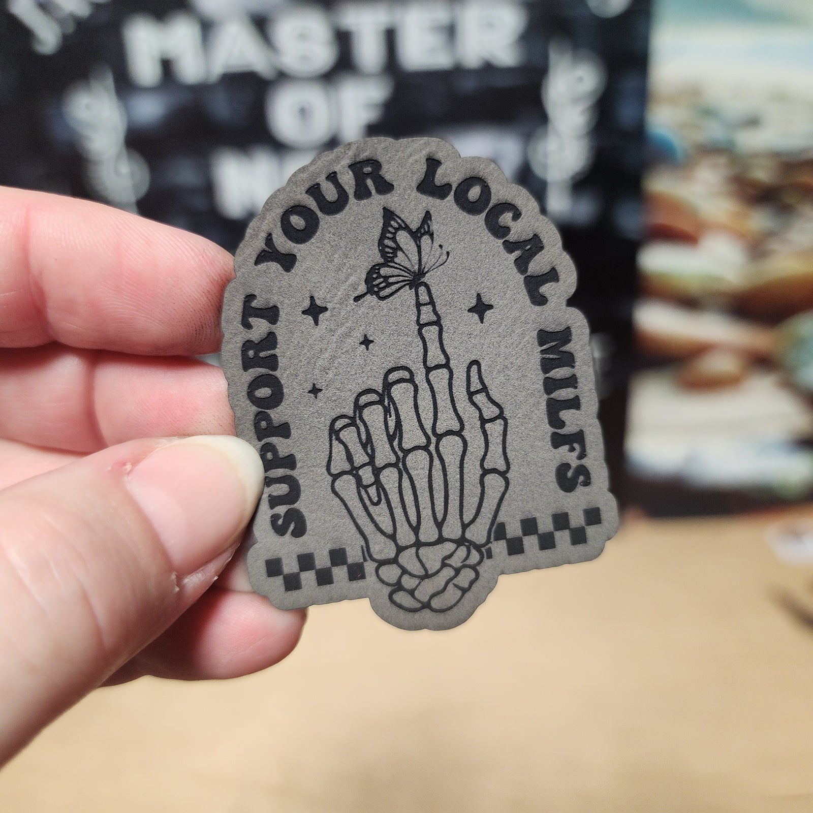 Support Your Local MILFs leatherette hat patch featuring a skeleton hand and butterfly design for quirky fashion.