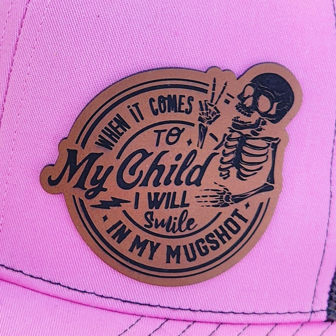 Funny leatherette hat patch for parents, 'My Child I Will Smile in My Mugshot', great for Halloween. 