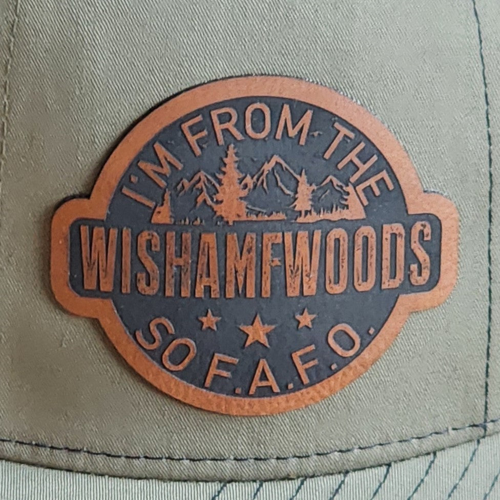 Leatherette hat patch saying "I'm From The Wishamwoods" with mountains and trees, perfect for outdoor enthusiasts.