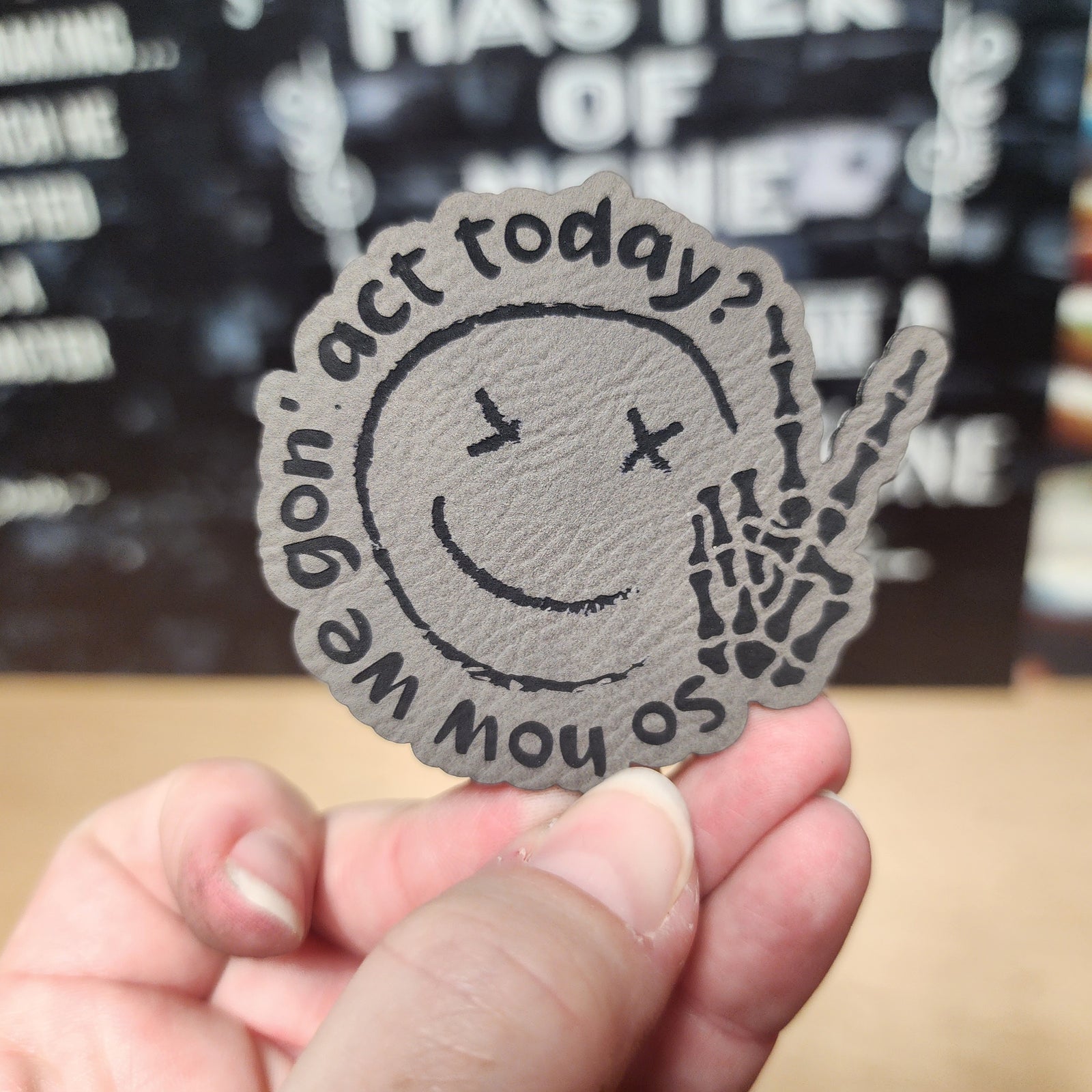 Unique leatherette hat patch with a smiley face and skeleton hand, perfect for custom accessories.
