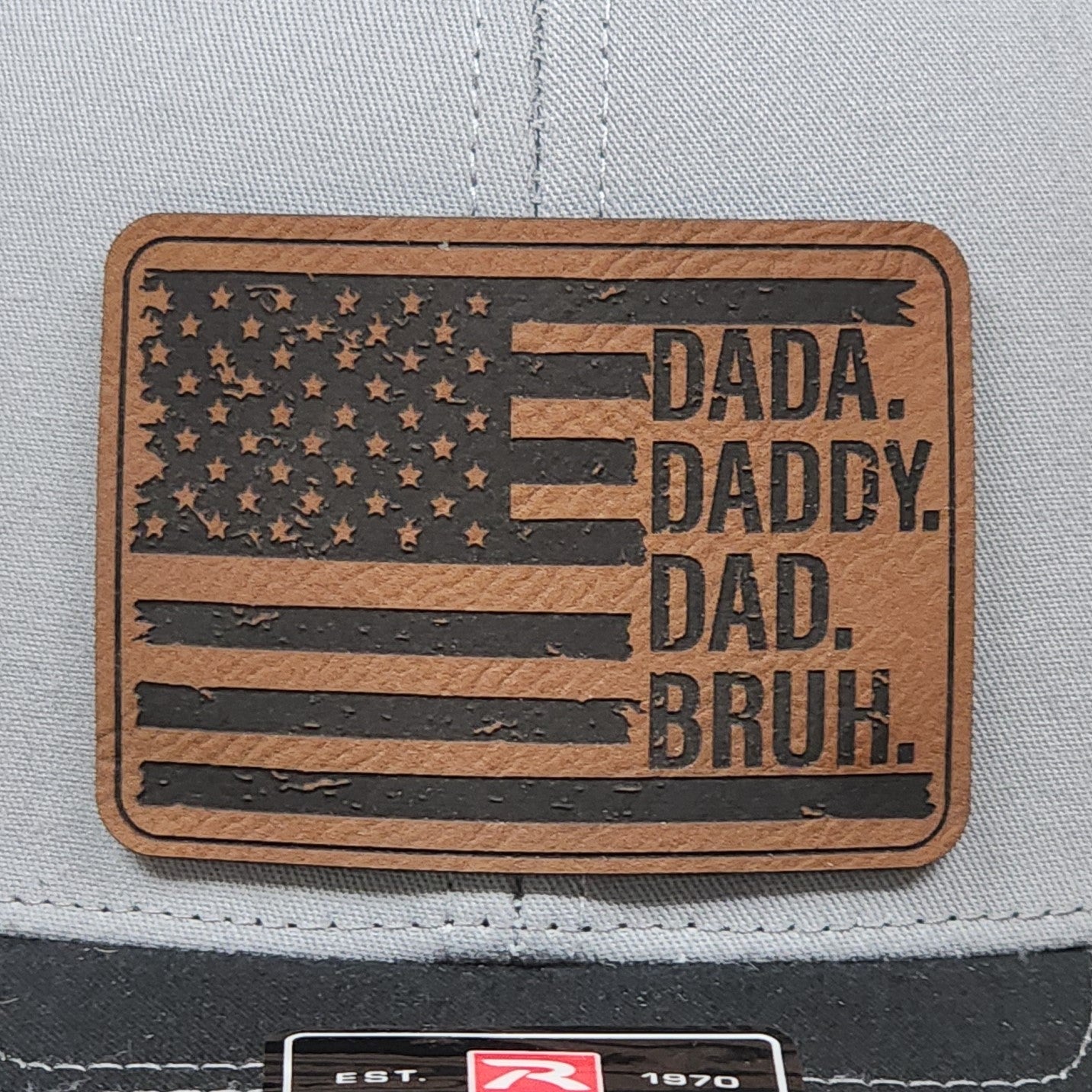 Leatherette hat patch featuring American flag design with humorous dad titles: Dada, Daddy, Dad, Bruh.