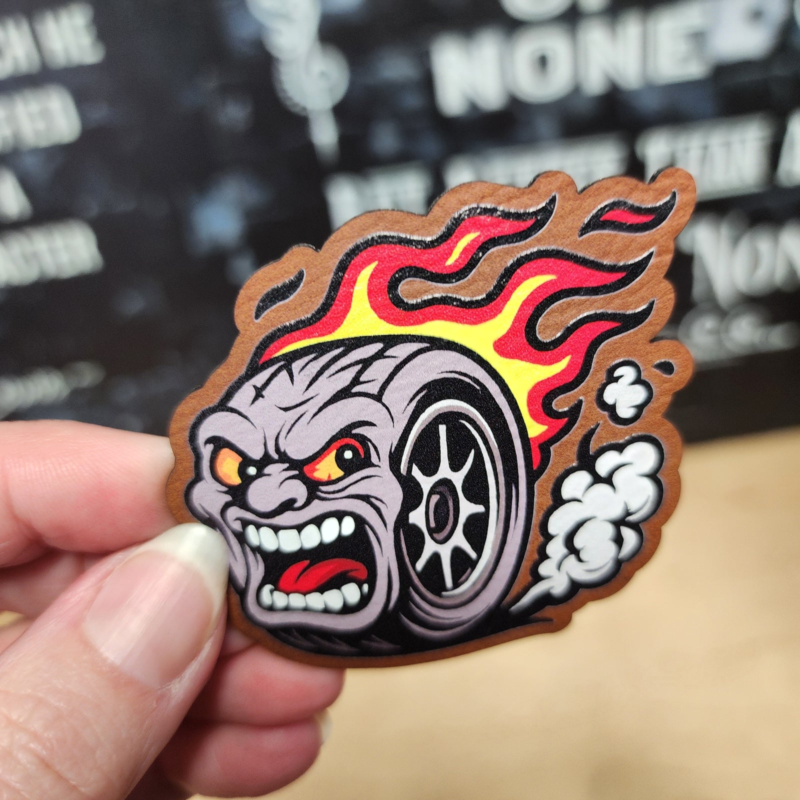 Racing tire logo leatherette patch featuring a fierce flaming tire character, perfect for car enthusiasts.