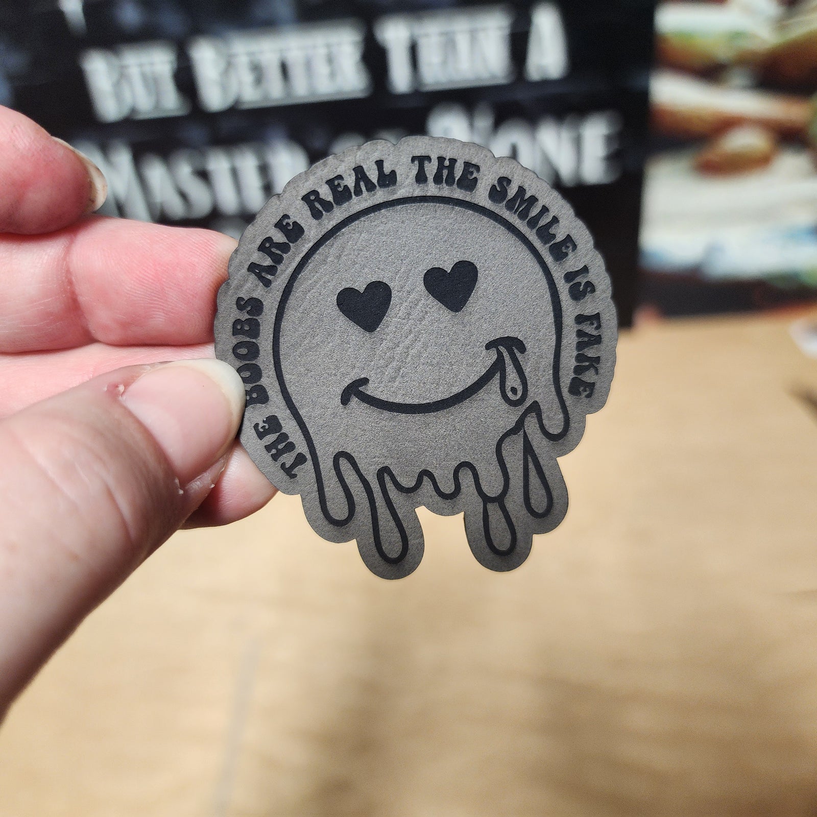Funny leatherette hat patch with a dripping smiley face and playful text, perfect for casual wear and humorous accessories.
