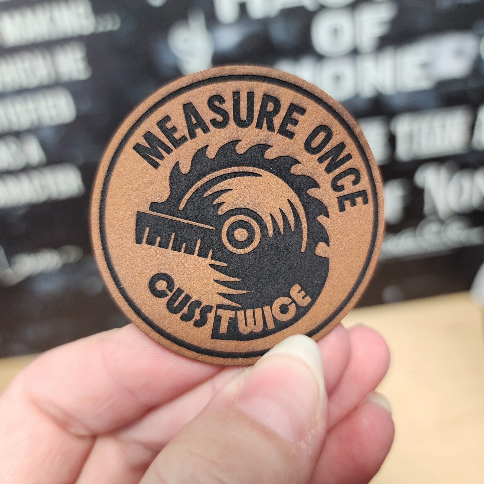 Leatherette work patch featuring 'Measure Once, Cut Twice' with a circular saw design for woodworking enthusiasts.