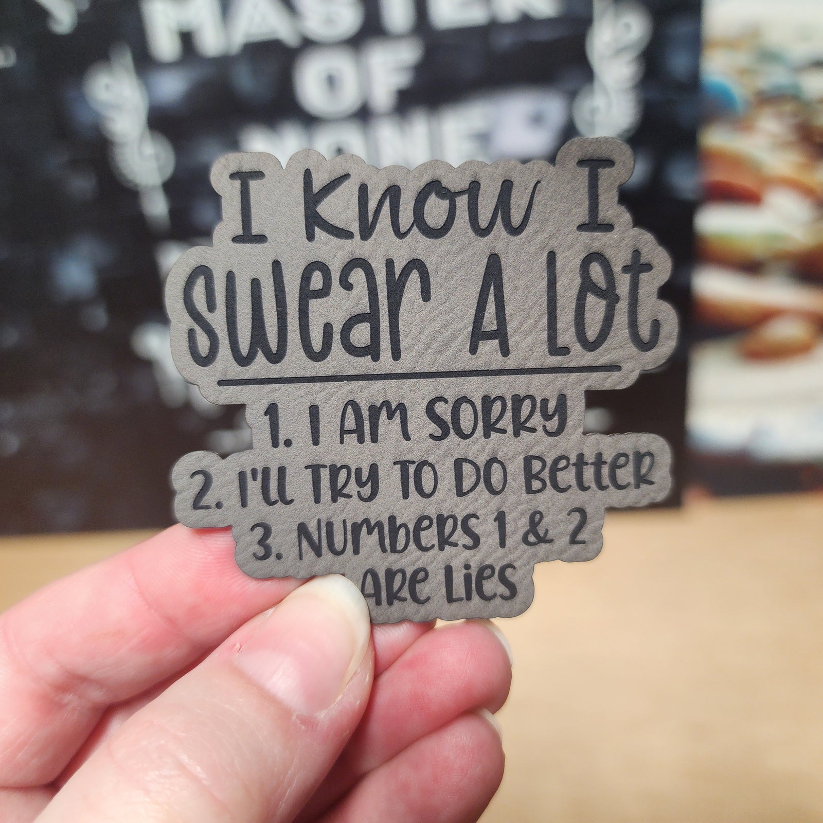 Funny leatherette hat patch 'I Know I Swear A Lot' with humorous apology list for quirky fashion accessories.