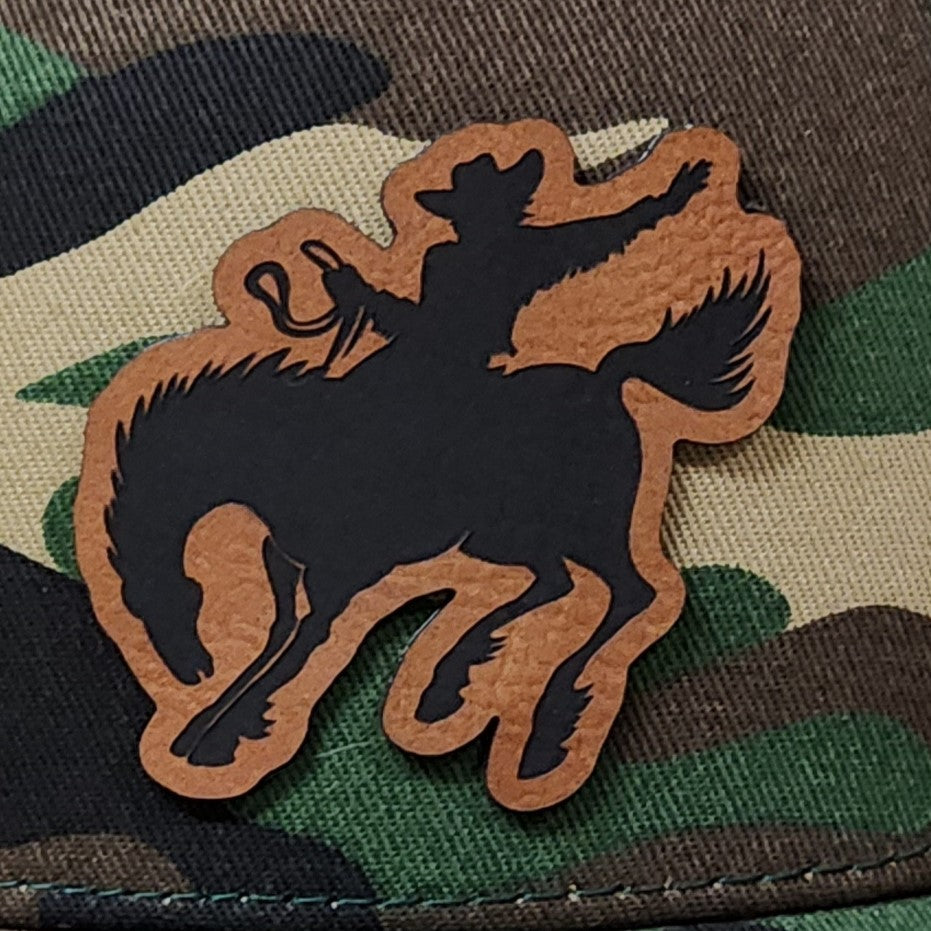 Cowboy leatherette hat patch with silhouette on camo background, perfect for western and rodeo enthusiasts.