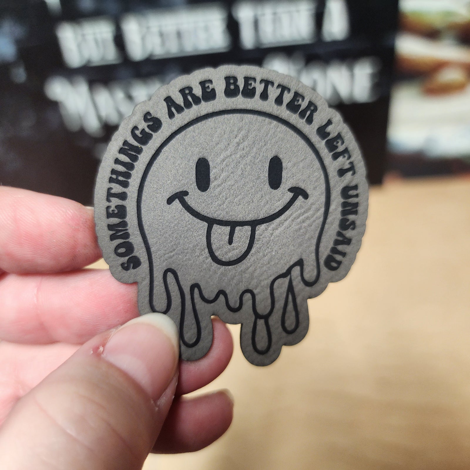 Funny leatherette hat patch with a smiling ghost and the phrase 'Some things are better left unsaid' for quirky accessories.