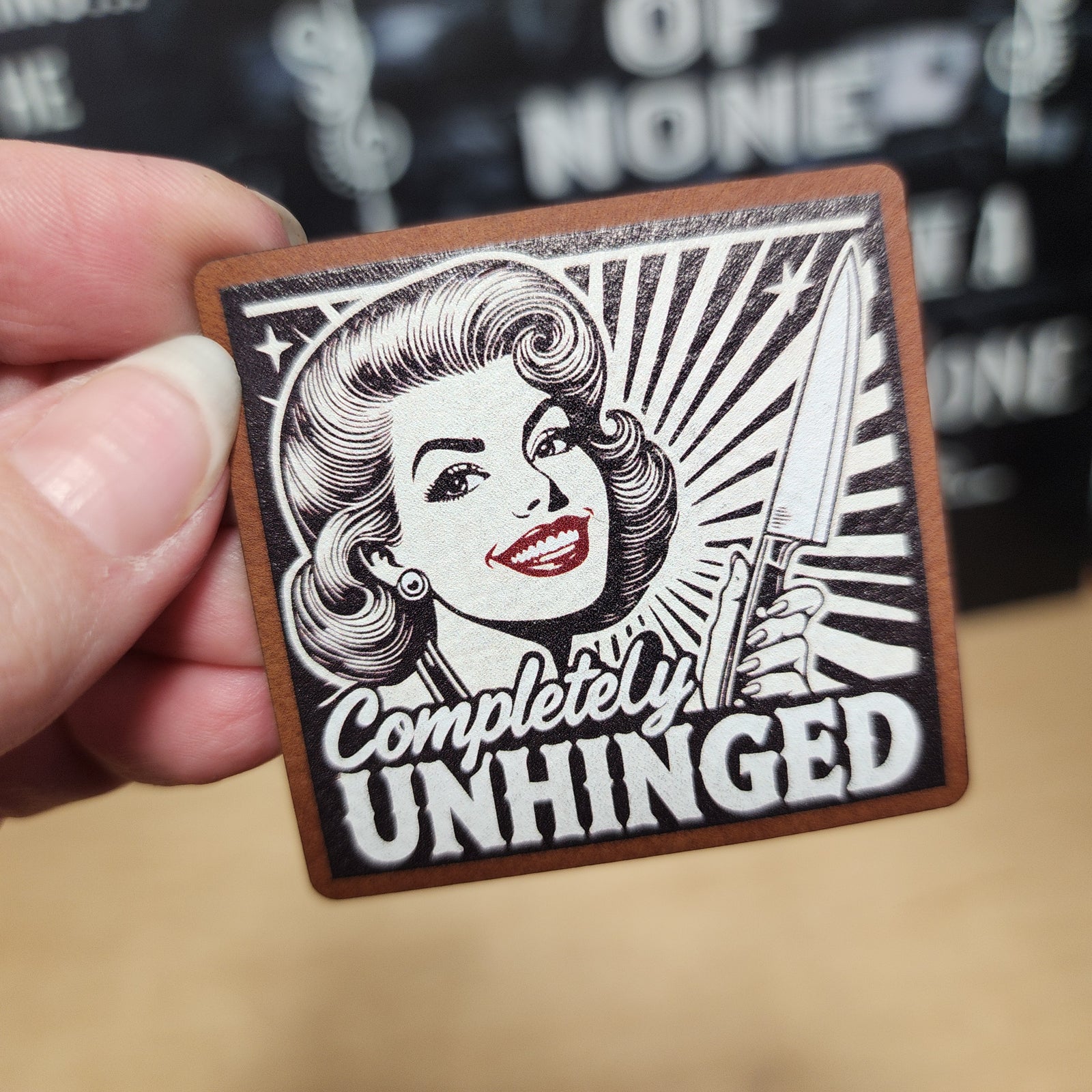 Completely Unhinged leatherette hat patch featuring vintage style graphic with woman holding a knife.
