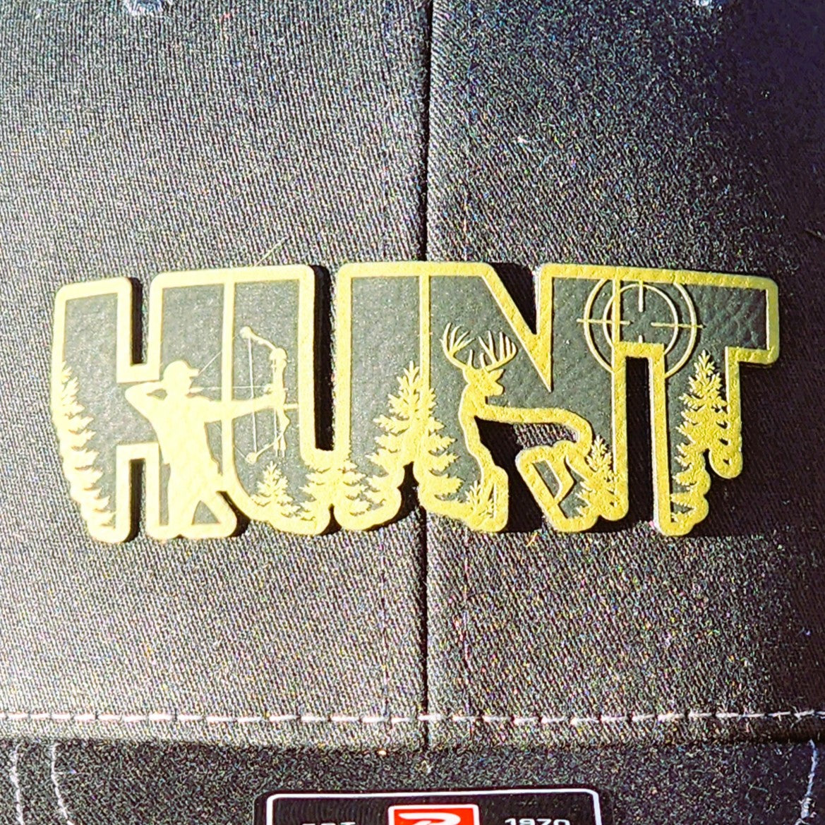 HUNT leatherette hat patch featuring a bow hunter, deer, and pine trees for outdoor enthusiasts.