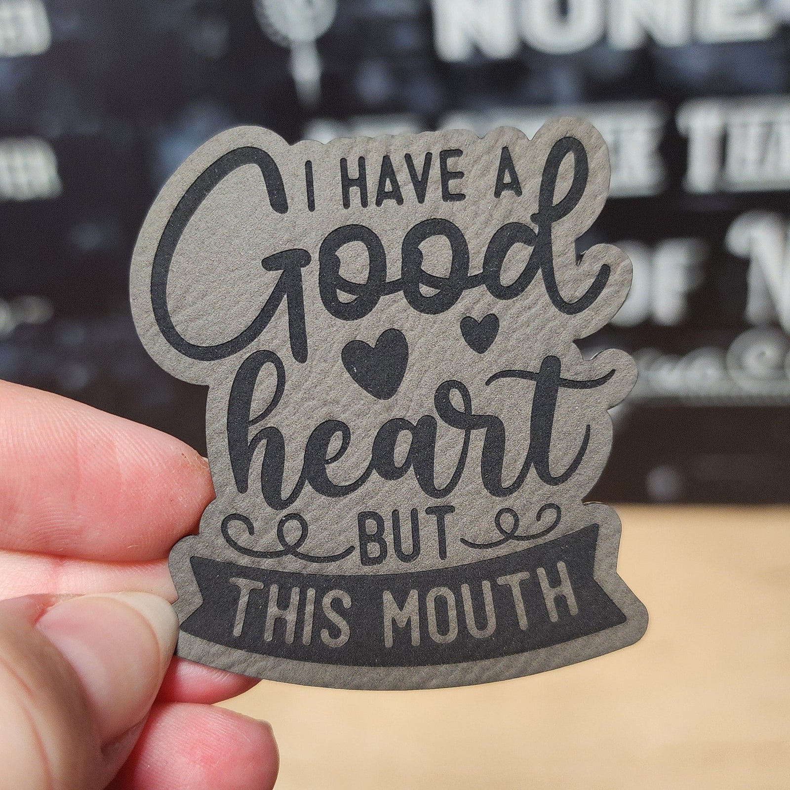 Funny leatherette hat patch reading 'I have a good heart but this mouth' for quirky hats and accessories.