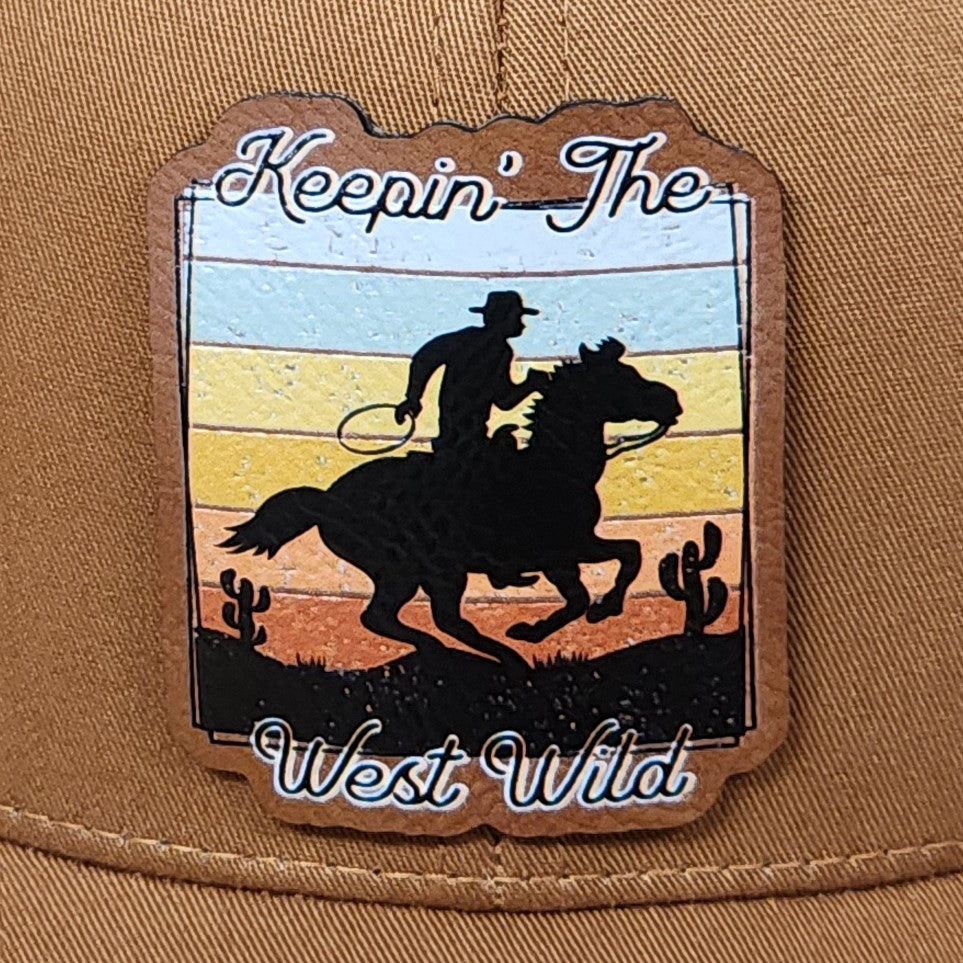 Keepin' The West Wild leatherette hat patch featuring a cowboy on horseback and desert scenery.