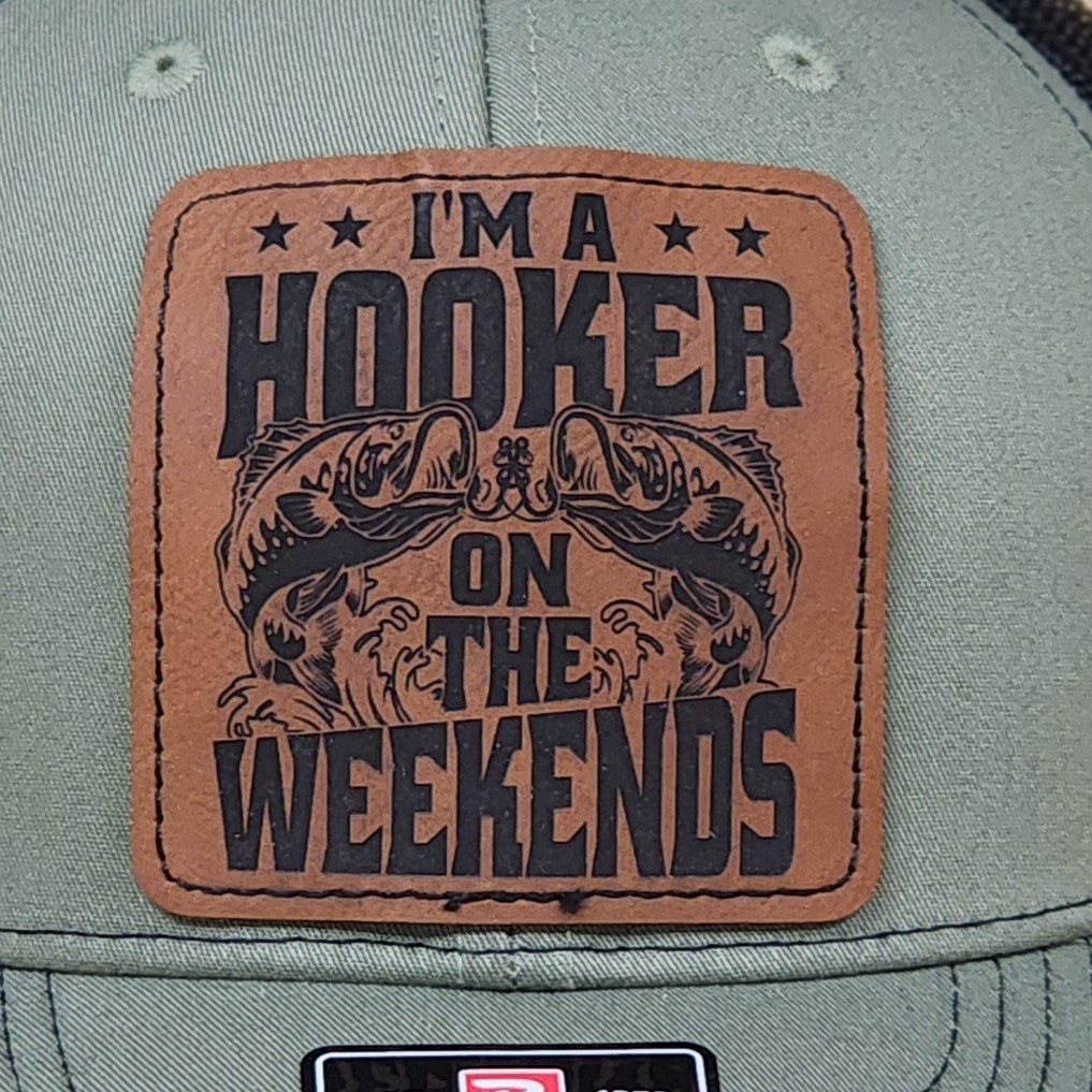 Leatherette hat patch saying 'I'm a Hooker on the Weekends' featuring fish design, perfect for fishing enthusiasts.