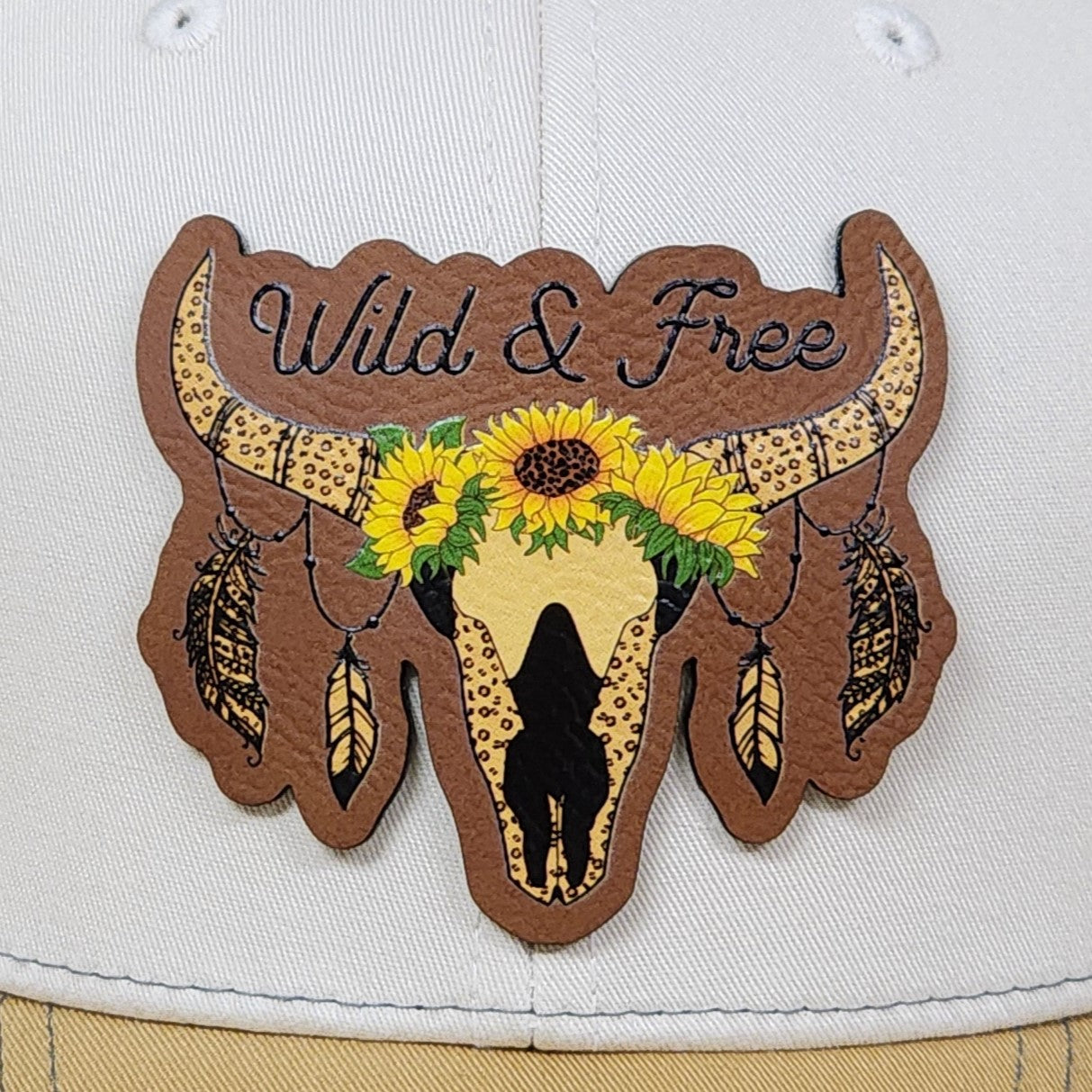 Wild & Free leatherette hat patch featuring a cow skull, sunflowers, and feathers for bohemian style hats.