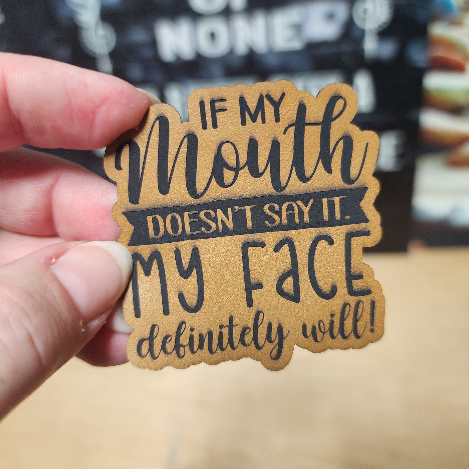 Funny leatherette hat patch with the quote 'If my mouth doesn't say it, my face definitely will!' for casual wear.