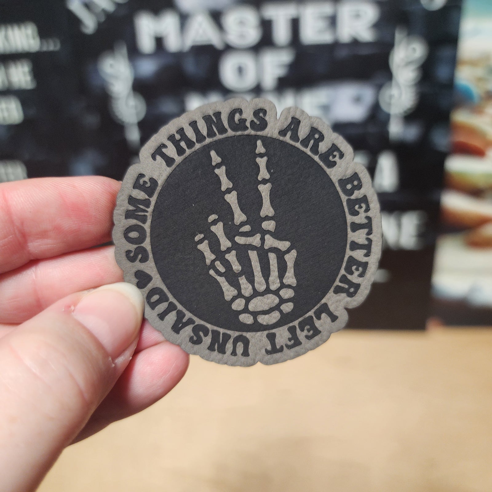 Skeleton hand leatherette patch with saying, 'Some things are better left unsaid' for edgy cap or backpack decor.