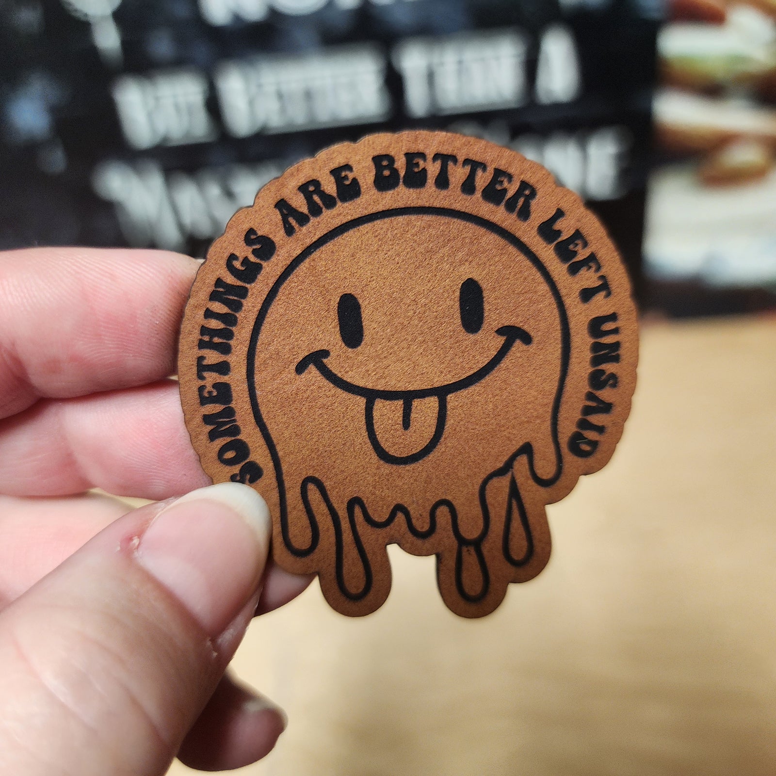 Funny leatherette hat patch with a smiling face and the phrase 'Something's are better left unsaid', perfect for gifts.