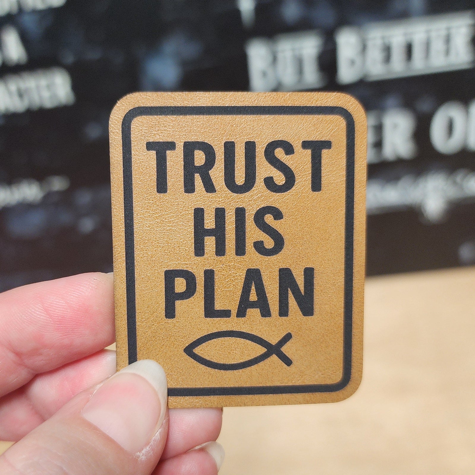 Inspirational leatherette hat patch with 'Trust His Plan' and fish symbol, perfect for faith-based apparel and accessories.