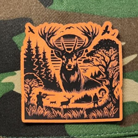 Hunting themed leatherette hat patch featuring a majestic stag scene with trees and silhouettes of hunters.