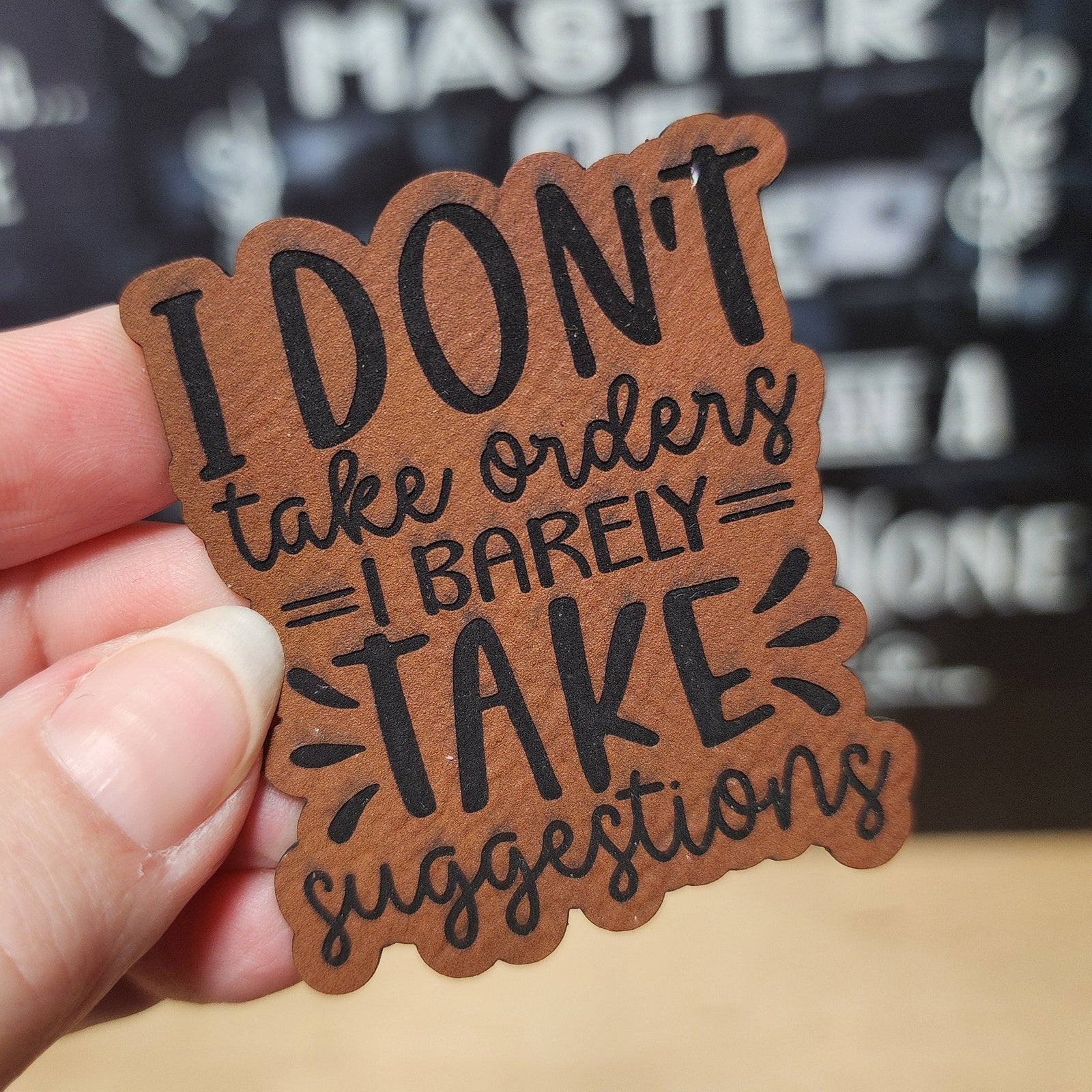 Funny leatherette hat patch with quote: "I Don't Take Orders, I Barely Take Suggestions" for trendy hats.
