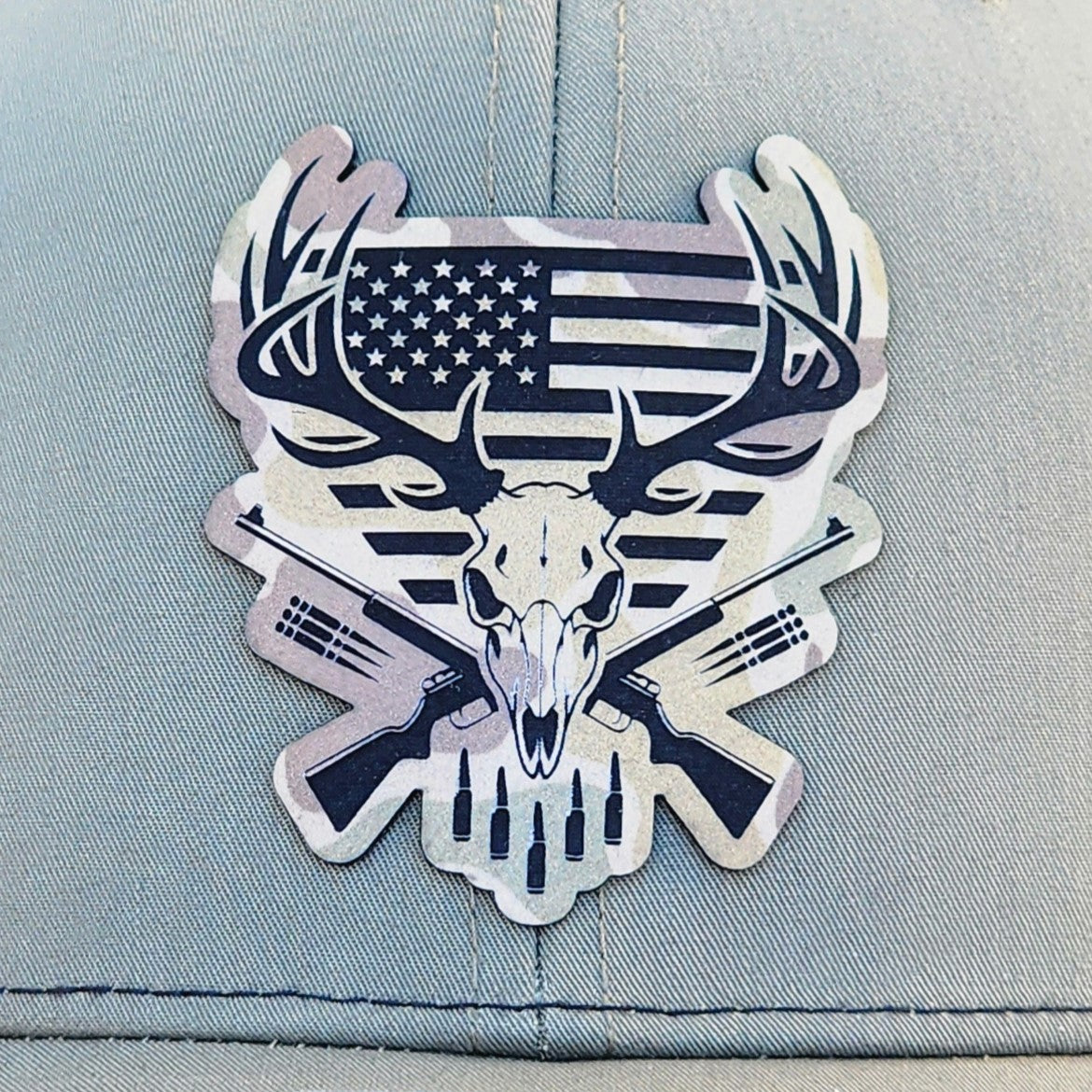 Patriotic deer skull leatherette hat patch with crossed rifles and American flag design for outdoor enthusiasts.